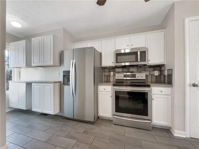 kitchen featuring decorative backsplash, stainless steel appliances, and white cabinets