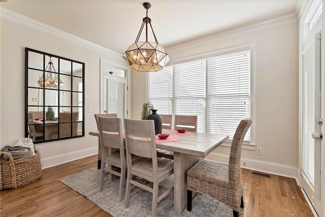 dining area featuring ornamental molding, wood-type flooring, and a notable chandelier