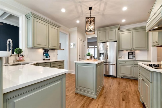 kitchen with stainless steel refrigerator with ice dispenser, sink, hanging light fixtures, black electric cooktop, and a kitchen island