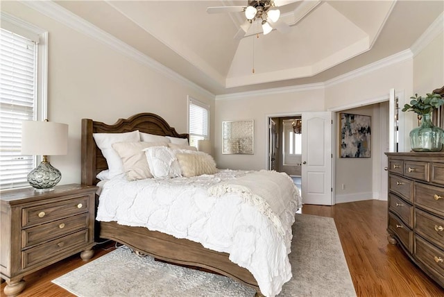 bedroom with lofted ceiling, ornamental molding, a tray ceiling, dark hardwood / wood-style floors, and ceiling fan