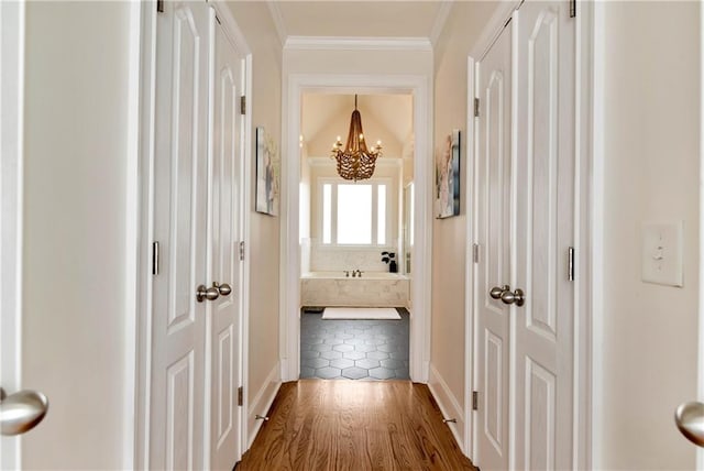 corridor with hardwood / wood-style flooring, ornamental molding, and a chandelier