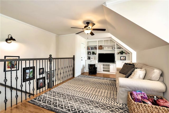 living room featuring built in shelves, ceiling fan, crown molding, and hardwood / wood-style floors