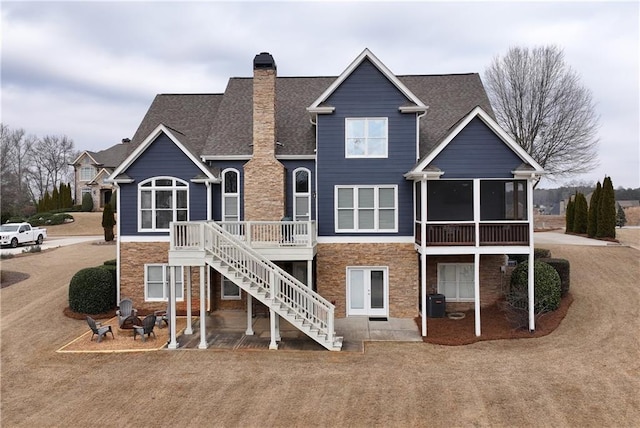 rear view of property with a wooden deck, a sunroom, and a patio area