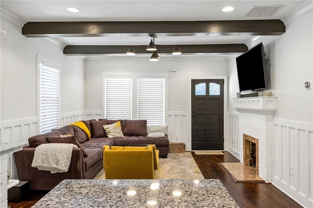 living area with a wainscoted wall, beamed ceiling, and dark wood finished floors