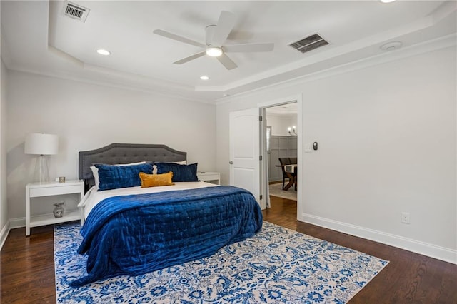 bedroom with dark wood-type flooring, a raised ceiling, and visible vents