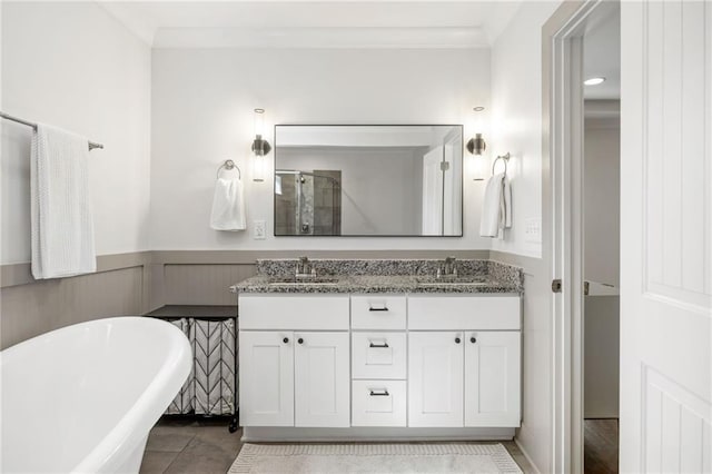 full bathroom featuring a wainscoted wall, double vanity, a soaking tub, and a sink