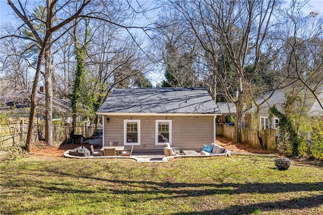 rear view of property with a fire pit, a patio, a lawn, and a fenced backyard