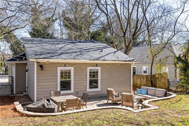 rear view of house featuring an outdoor living space with a fire pit, a shingled roof, a patio area, and fence