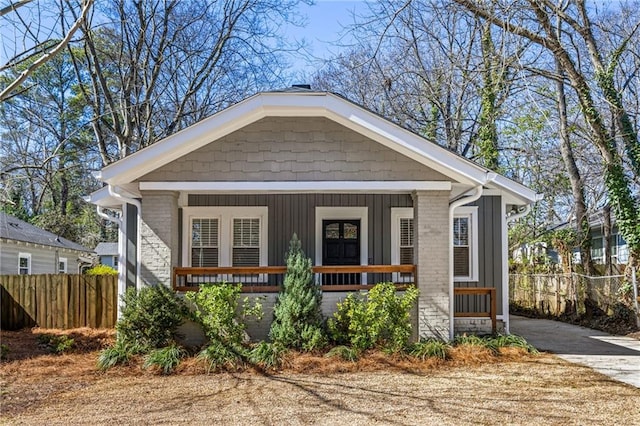 bungalow featuring driveway, fence, a porch, and board and batten siding