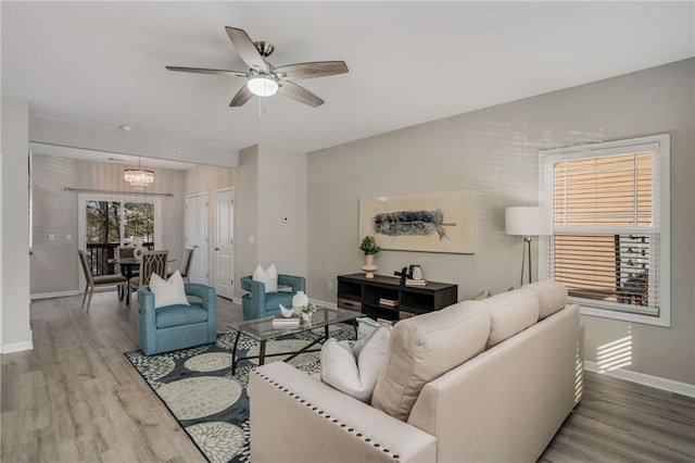 living room with ceiling fan, baseboards, and wood finished floors