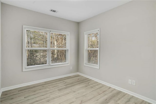 unfurnished room featuring visible vents, light wood finished floors, and baseboards