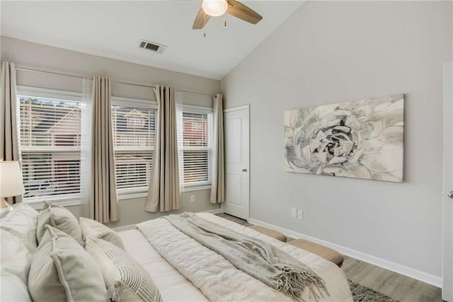 bedroom featuring lofted ceiling, visible vents, multiple windows, and wood finished floors