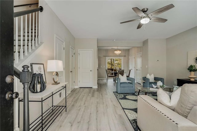 living room with ceiling fan, stairway, light wood-type flooring, and baseboards