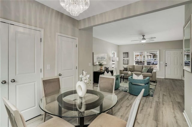 dining area featuring ceiling fan with notable chandelier, baseboards, and wood finished floors