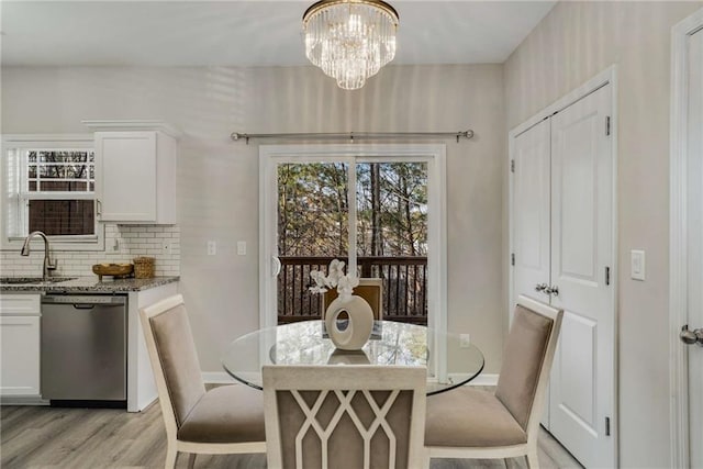 dining space featuring light wood-style flooring, a chandelier, and baseboards