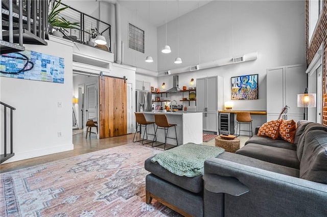 living room featuring sink, beverage cooler, a barn door, and a high ceiling