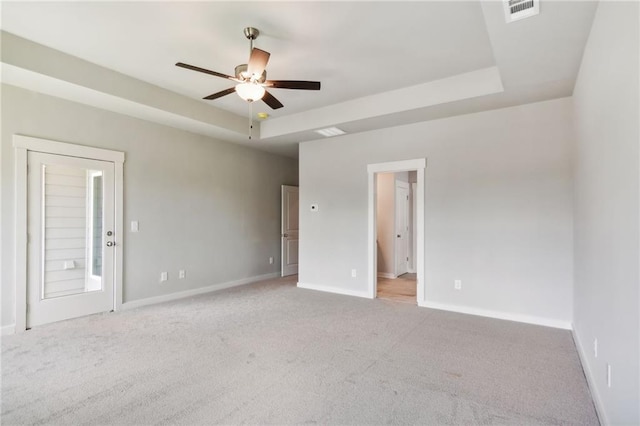 carpeted empty room with ceiling fan and a raised ceiling