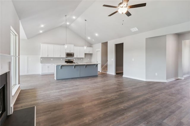 kitchen with hanging light fixtures, white cabinetry, hardwood / wood-style floors, and an island with sink