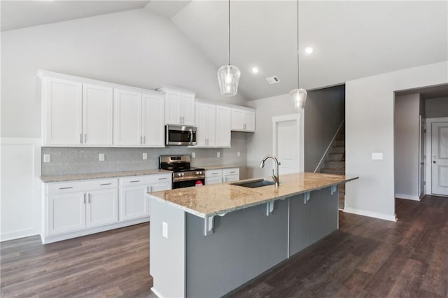 kitchen with hanging light fixtures, white cabinetry, appliances with stainless steel finishes, and a center island with sink