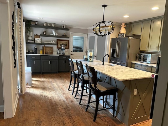 kitchen with wood-type flooring, a kitchen island with sink, a notable chandelier, gray cabinetry, and high end fridge