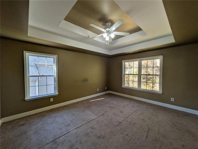 empty room with ceiling fan, carpet, baseboards, and a raised ceiling