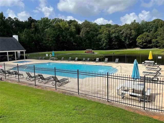 pool with a lawn, a patio area, and fence