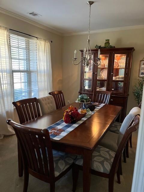 carpeted dining space featuring a chandelier and crown molding