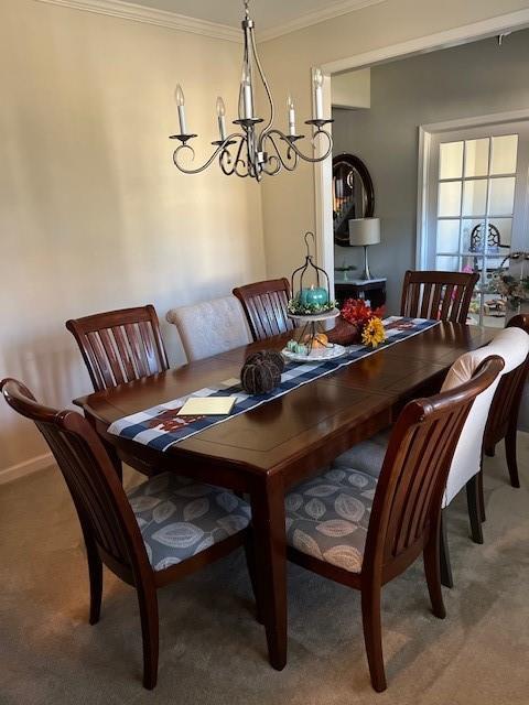 dining area featuring carpet floors, an inviting chandelier, and crown molding