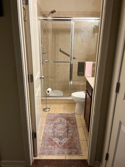 bathroom with tile patterned floors, vanity, an enclosed shower, and toilet