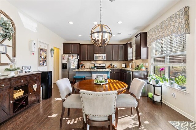 dining room with ceiling fan with notable chandelier and dark wood-type flooring