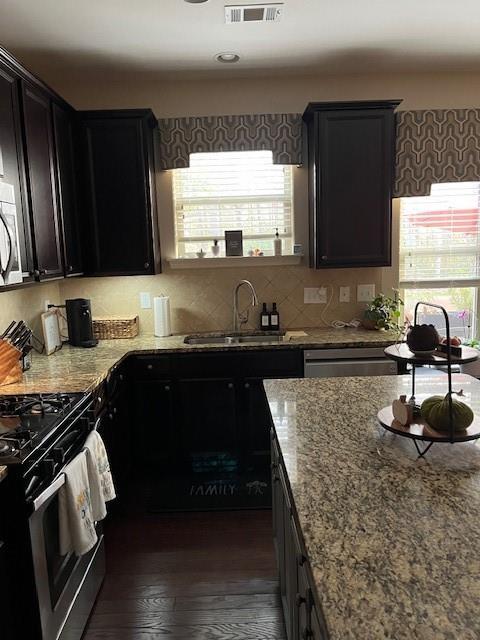 kitchen featuring light stone countertops, decorative backsplash, gas stove, sink, and dark hardwood / wood-style floors