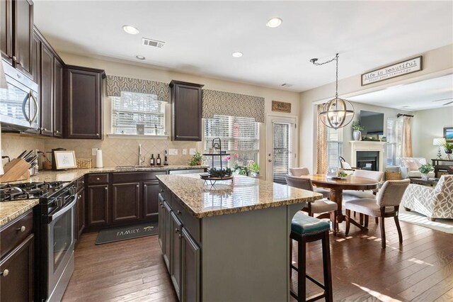 kitchen with decorative backsplash, appliances with stainless steel finishes, light stone countertops, and dark brown cabinets