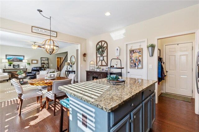 kitchen featuring tasteful backsplash, light stone counters, dark hardwood / wood-style floors, a breakfast bar, and appliances with stainless steel finishes