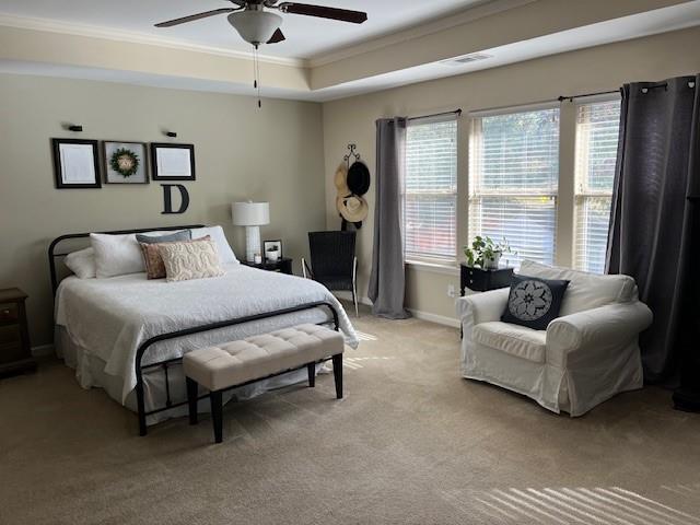 carpeted bedroom featuring a raised ceiling, ceiling fan, and crown molding