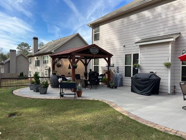 rear view of property with a gazebo, a patio area, and a lawn