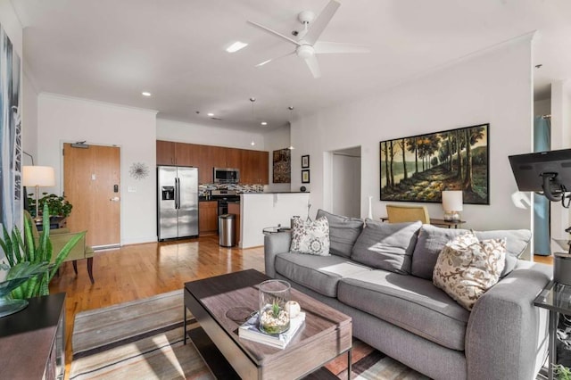 living room with ornamental molding, ceiling fan, and light hardwood / wood-style flooring