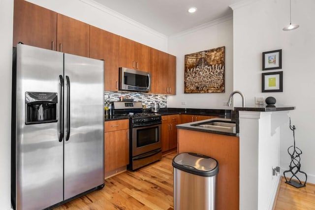 kitchen with appliances with stainless steel finishes, decorative light fixtures, sink, ornamental molding, and kitchen peninsula