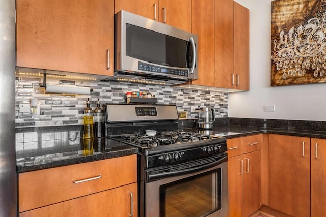 kitchen featuring stainless steel appliances, decorative backsplash, and dark stone counters