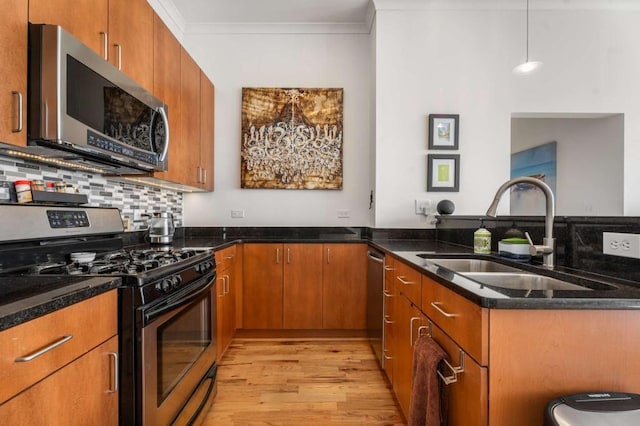 kitchen with pendant lighting, sink, stainless steel appliances, and dark stone counters