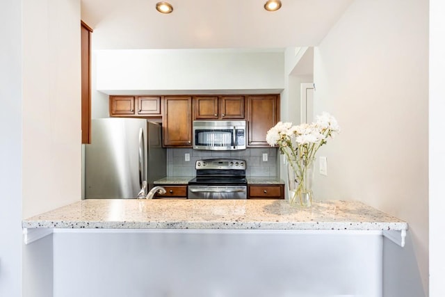 kitchen with decorative backsplash, light stone countertops, stainless steel appliances, and kitchen peninsula