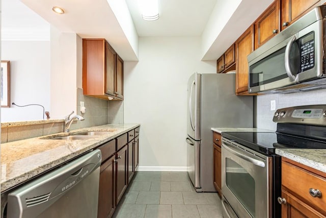 kitchen featuring appliances with stainless steel finishes, backsplash, light stone counters, sink, and light tile patterned floors