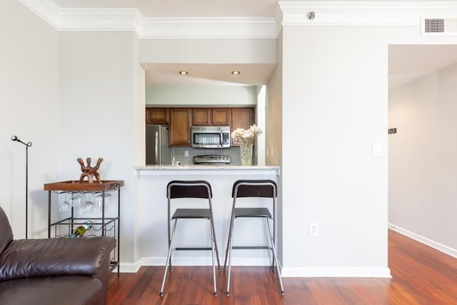 kitchen featuring stainless steel appliances, tasteful backsplash, kitchen peninsula, crown molding, and a breakfast bar