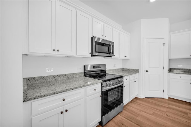 kitchen with white cabinetry, appliances with stainless steel finishes, light stone counters, and light wood-style floors