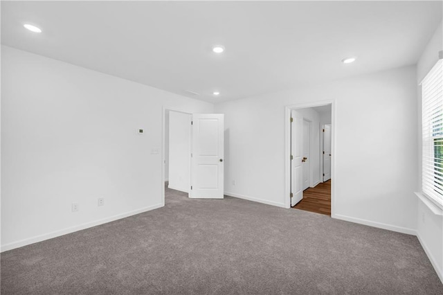 unfurnished bedroom with dark colored carpet, recessed lighting, and baseboards