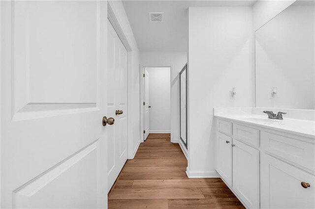bathroom with vanity, baseboards, a shower stall, wood finished floors, and visible vents