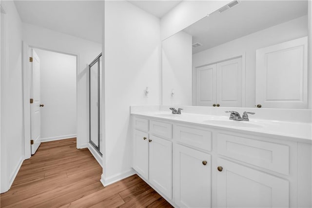 full bath featuring a sink, a stall shower, wood finished floors, and visible vents