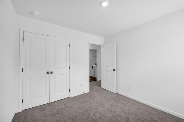 unfurnished bedroom with carpet floors, baseboards, washer / clothes dryer, and a closet