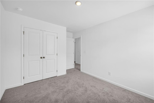 unfurnished bedroom with carpet floors, baseboards, and a closet