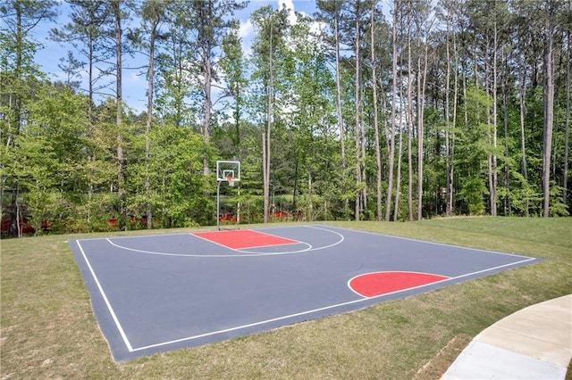 view of basketball court with a lawn and basketball hoop