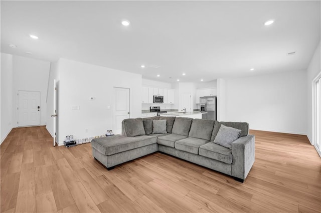 living area with recessed lighting, baseboards, and light wood-type flooring